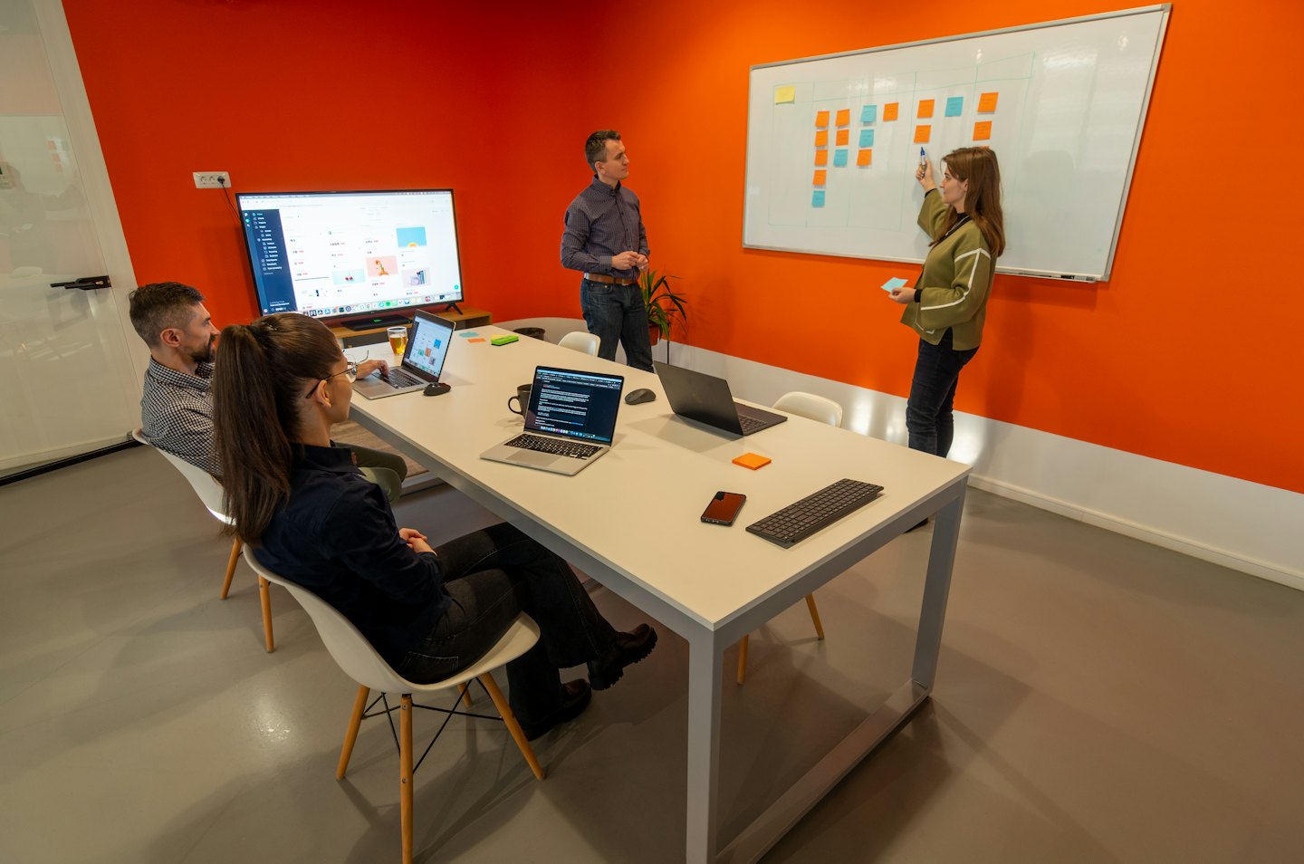 Team collaborating in a modern office with orange accents.